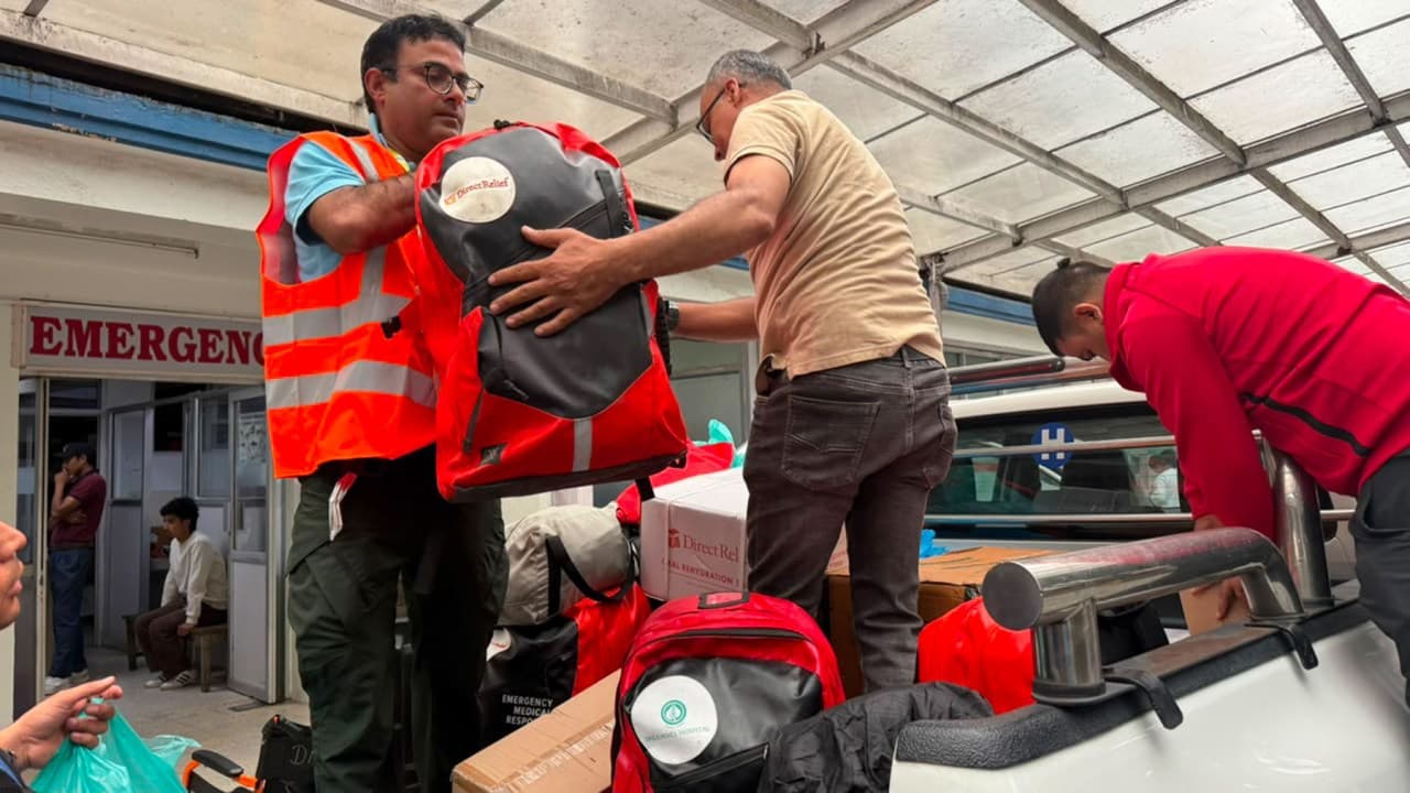 A medical response team loading emergency supplies onto a vehicle outside a hospital emergency entrance.